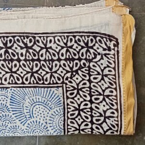 May include: A white cotton fabric with a black and blue block print design. The fabric has a gold border.