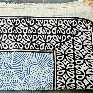 May include: A white cotton scarf with a black and blue geometric pattern. The scarf has a gold border.
