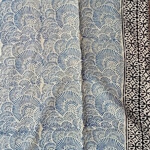 May include: A white cotton fabric with a blue and black printed design. The fabric features a repeating pattern of stylized floral motifs.