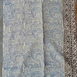 May include: A white fabric with a blue and black block print design. The fabric has a repeating pattern of stylized fans.