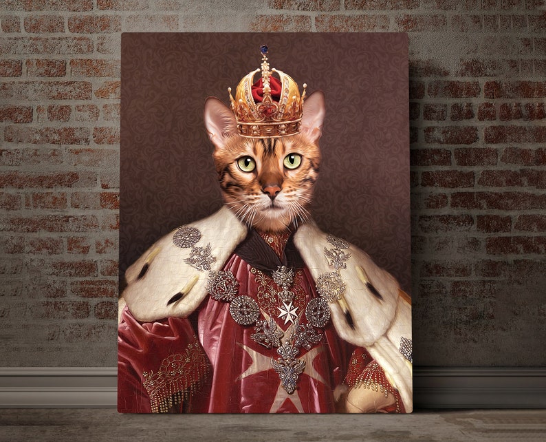 May include: A brown tabby cat wearing a gold crown and a red and white robe with gold trim. The cat is looking directly at the viewer.