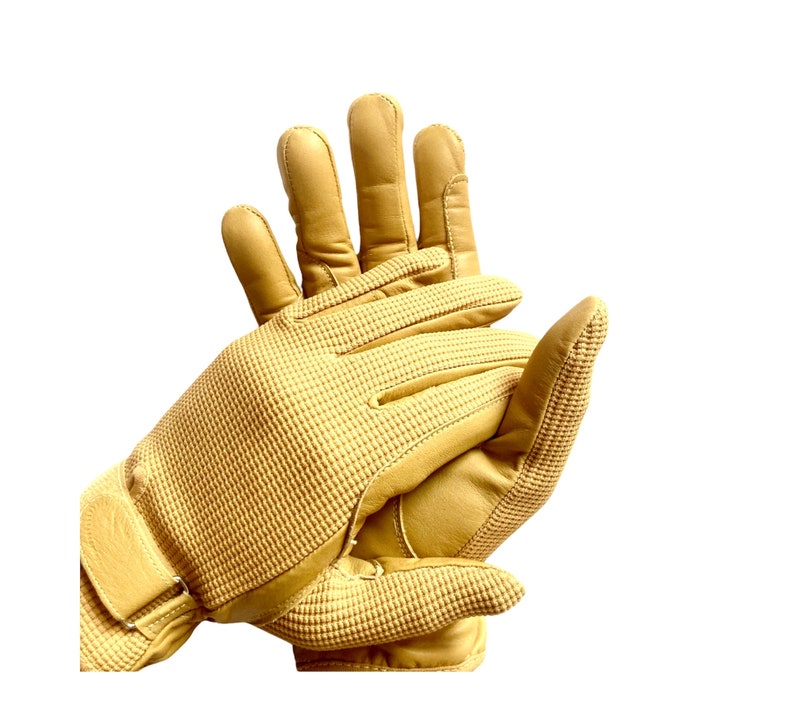 May include: A pair of tan leather gloves with a textured pattern on the back of the hand. The gloves have a wrist strap and are designed for outdoor activities.