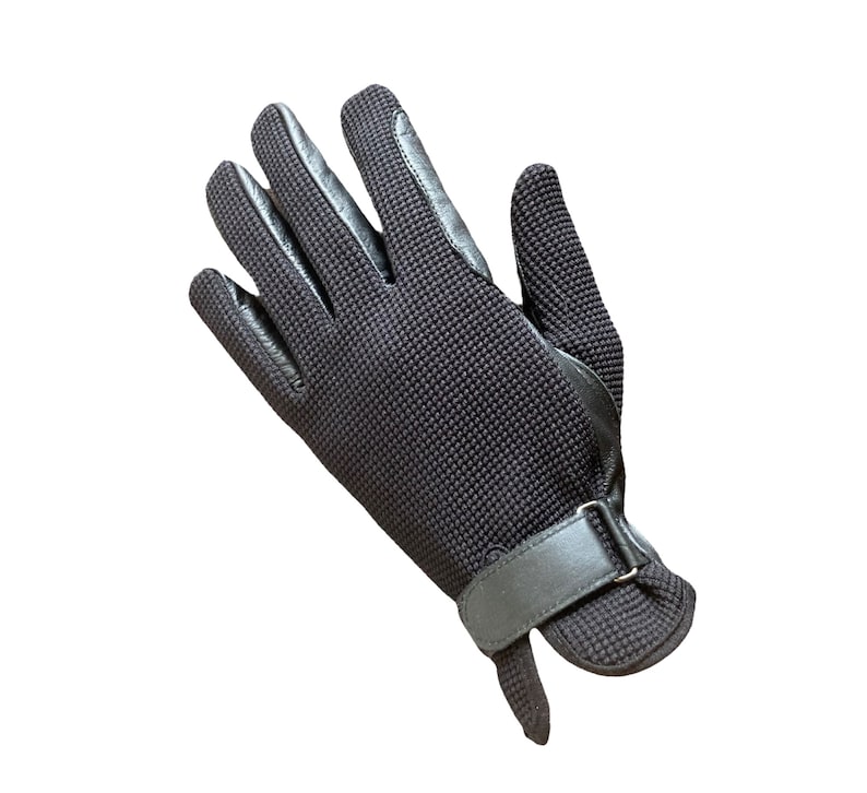 May include: Black leather riding gloves with a textured fabric back and a velcro strap closure.