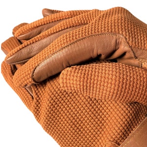 May include: A pair of brown leather and brown knit gloves with a textured knit pattern. The gloves are folded together with the leather palm facing out.