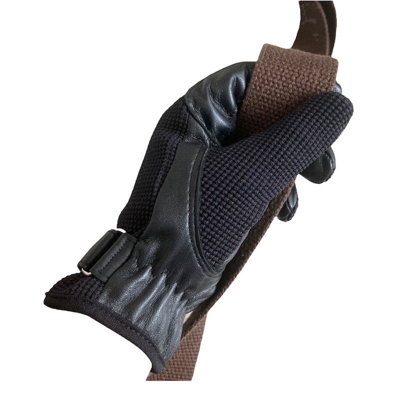 May include: A black leather and mesh riding glove with a brown strap. The glove has a buckle closure and a textured palm.