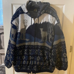 Peut inclure: Un sweat à capuche avec une fermeture éclair et un cordon de serrage au bas. Le sweat est fait d'un tissu épais et tricoté et présente un motif bleu, vert et blanc avec des silhouettes de cerfs. Le sweat a une étiquette qui indique "Southwestern".