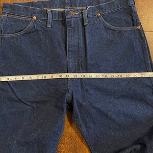 Puede incluir: Un par de pantalones vaqueros de mezclilla azul oscuro con corte recto. Los vaqueros tienen un dise&ntilde;o cl&aacute;sico de cinco bolsillos y cierre de bot&oacute;n. La medida de la cintura es de 63,5 cm.