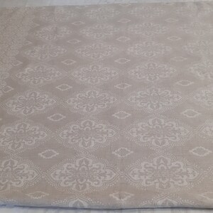 May include: A beige fabric with a white damask pattern. The fabric has a subtle sheen and a soft texture.
