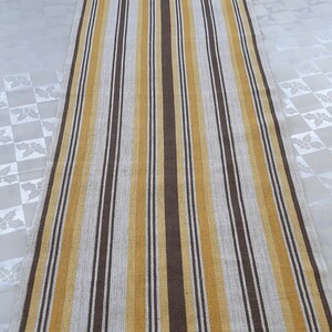 May include: A long, narrow rug with alternating stripes of brown, beige, and gold.