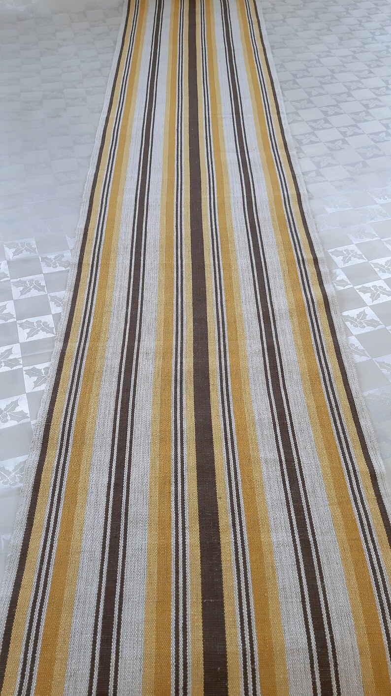 May include: A long, narrow rug with alternating stripes of brown, beige, and gold.