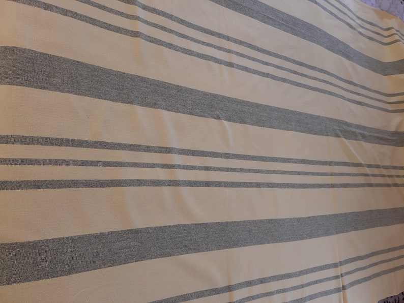 May include: A beige and gray striped fabric with a subtle texture. The fabric has a horizontal stripe pattern with alternating beige and gray stripes.