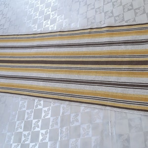 May include: A long, striped runner rug with alternating brown and yellow stripes. The rug is made of a woven fabric and has a subtle texture.