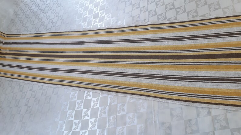 May include: A long, striped runner rug with alternating brown and yellow stripes. The rug is made of a woven fabric and has a subtle texture.
