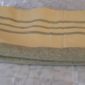 May include: A folded yellow and gray striped throw blanket. The blanket is made of a soft, woven fabric.