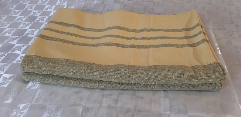 May include: A folded yellow and gray striped throw blanket. The blanket is made of a soft, woven fabric.
