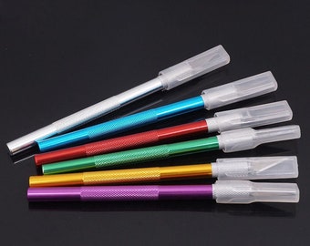 May include: Six craft knives with clear plastic handles and colored metal shafts. The colors are purple, yellow, green, red, blue, and silver.
