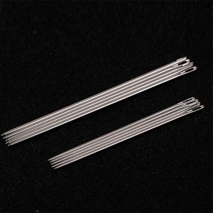 Pode incluir: Um conjunto de 10 agulhas de costura prateadas, dispostas em duas filas. As agulhas são afiadas e pontiagudas, com um pequeno olho na parte superior. São ideais para costurar à mão e bordar.