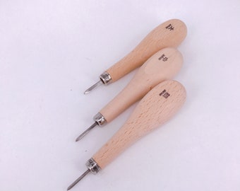 May include: Three wooden-handled awls with metal tips. The handles are light brown and have Japanese text on them.
