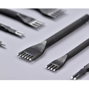 Puede incluir: Un juego de ocho herramientas de costura de cuero con agujas de diferentes tamaños. Las herramientas están hechas de metal y tienen un acabado negro. Las agujas son afiladas y puntiagudas.