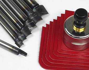 May include: A collection of leatherworking tools, including a set of metal punches, a round leather cutter, and several red leather corner pieces. The tools are arranged on a white surface, showcasing their design and functionality.