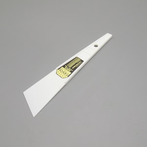 May include: White plastic scraper with a black and gold label that reads "S.V.C. 3.5" and "Made in Japan".