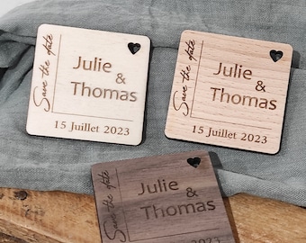 May include: Three wooden save the date cards with a heart cutout. The cards are different shades of brown and feature the text "Save the date" and "Julie & Thomas" with the date "15 Juillet 2023".