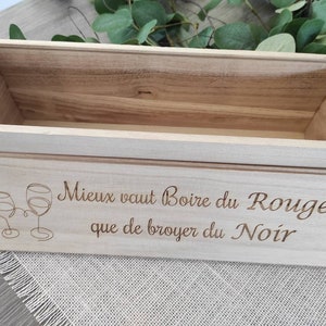 Peut inclure: Une caisse à vin en bois clair avec un couvercle coulissant. Le couvercle est gravé de deux verres à vin et de la phrase française "Mieux vaut Boire du Rouge que de broyer du Noir". La boîte est vide.