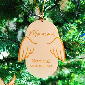 Peut inclure: Une décoration de Noël en bois blanc avec des ailes dorées et les mots "Maman" et "Notre ange pour toujours".