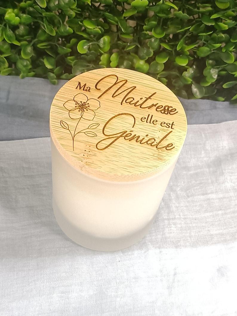 May include: A wooden candle lid with a floral design and the text "Ma Maitresse elle est Geniale".