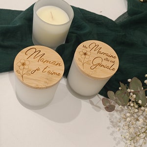 May include: Two white frosted glass candle jars with wooden lids. The lids are engraved with the text "Maman je t'aime" and "Ma Marraine elle est Geniale".