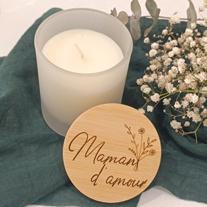 May include: A white frosted glass candle with a wooden lid. The lid is engraved with the text "Maman d'amour" and a floral design.