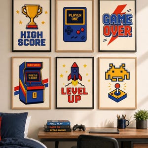 Puede incluir: Un conjunto de seis láminas de pared enmarcadas con diseños de pixel art. Las impresiones muestran un trofeo dorado con el texto HIGH SCORE, una consola portátil azul con PLAYER ONE, un rayo rojo con GAME OVER, una máquina recreativa, un cohete con LEVEL UP y un alienígena amarillo con un joystick.