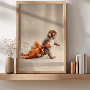 Könnte beinhalten: Gerahmter Druck, der einen jungen Affen zeigt, der ein orangefarbenes Stofftier zieht. Der Affe ist braun und weiß, mit einem neugierigen Ausdruck. Das Stofftier liegt auf einer hellen Oberfläche.