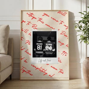 May include: A framed print featuring a black and white photo of two people wearing jerseys with the names "Rozanov" and "Hollander" and numbers 81 and 24. The print has handwritten red text and the words "Lily and Jane".