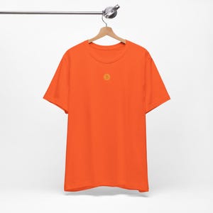 May include: Orange short-sleeved t-shirt with a small embroidered Bitcoin logo on the front.