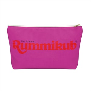 May include: A pink zippered pouch with the text "The Original Rummikub" in red.
