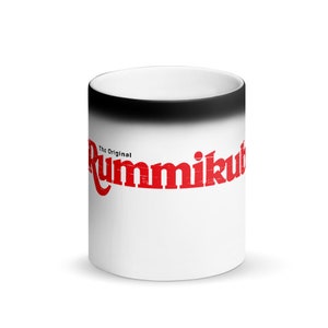 Op de afbeelding: Een witte keramische magische mok met een zwarte rand. De mok heeft de rode tekst "The Original Rummikub" aan de voorkant.