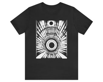 Può includere: T-shirt nero con un design grafico bianco. Il design è un motivo simmetrico di cerchi concentrici e linee radiali, che crea un effetto geometrico astratto. La maglietta è realizzata in un materiale morbido.