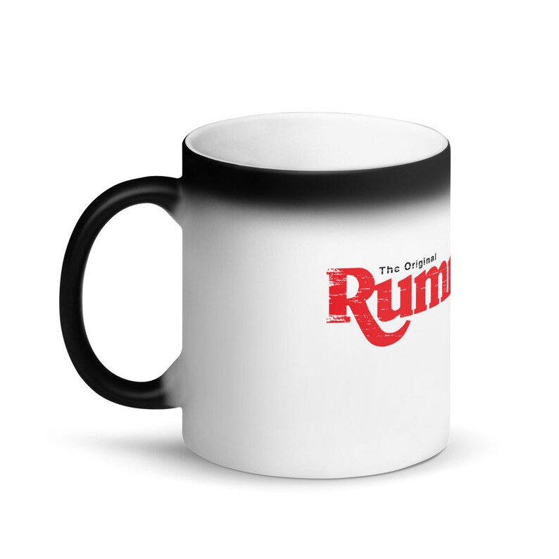 Op de afbeelding: Een zwart-witte magische mok met een rood logo met de tekst "The Original Rumble" op de witte kant.