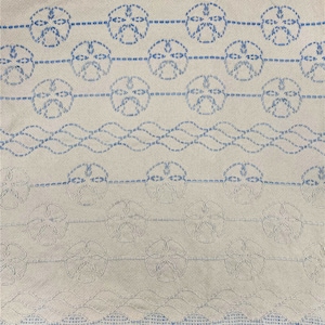 May include: A white woven throw blanket with a blue embroidered pattern of seashells. The blanket has a fringe border.