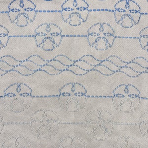 May include: A white fabric with a blue embroidered pattern of seashells. The pattern is repeated in rows across the fabric.