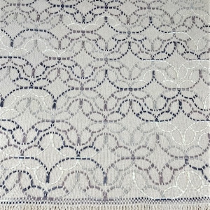 May include: A beige woven rug with a geometric pattern of black and brown lines. The rug has a fringe border.
