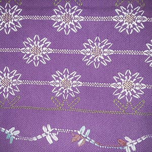 May include: Purple fabric with a white embroidered pattern of flowers. The flowers are arranged in rows and have a starburst design.
