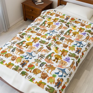 Peut inclure: Couverture blanche ornée de créatures de dessins animés colorées, dont des requins, des chats et des tasses à thé. La couverture est posée sur un lit avec un cadre en bois. La couverture présente un motif fantaisiste.