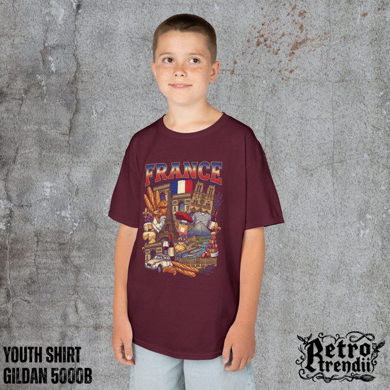 A young boy wearing a Red T-shirt featuring a colorful graphic design of France landmarks and symbols, including the Eiffel Tower, Notre-Dame, croissants, wine, and French fashion.