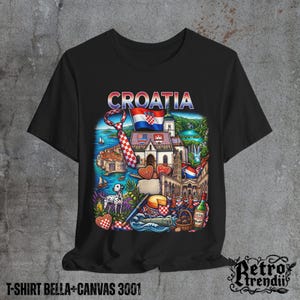 A black T-shirt featuring a colorful graphic design of Croatia landmarks and symbols, including a Dalmatian dog, necktie, Mediterranean coast, and historic architecture, displayed on a textured grey background.