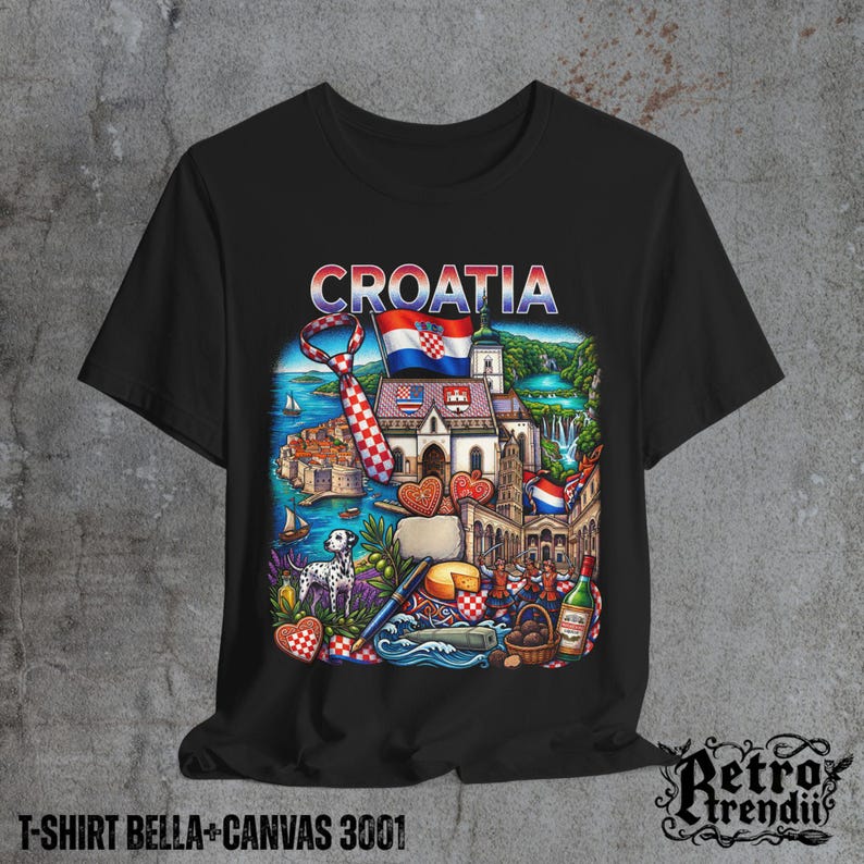 A black T-shirt featuring a colorful graphic design of Croatia landmarks and symbols, including a Dalmatian dog, necktie, Mediterranean coast, and historic architecture, displayed on a textured grey background.