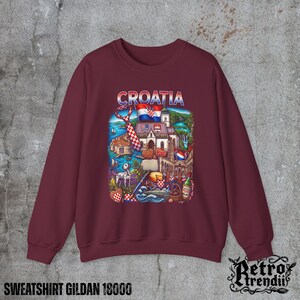 A Red crewneck sweatshirt featuring a detailed graphic design of Croatia landmarks and symbols, including a Dalmatian dog, necktie, Mediterranean coast, and historic architecture, displayed on a textured grey background.