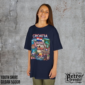 A young girl wearing a blue T-shirt featuring a colorful graphic design of Croatia landmarks and symbols, including a Dalmatian dog, necktie, Mediterranean coast, and historic architecture.