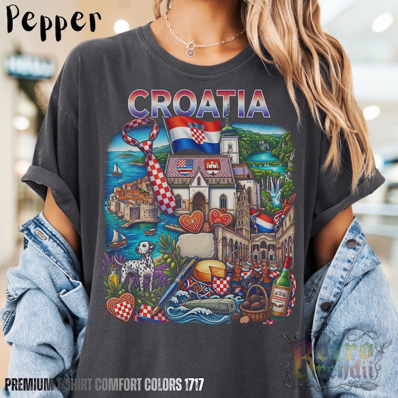 A person wearing a grey pepper acid-wash T-shirt featuring a colorful graphic design of Croatia landmarks and symbols, including a Dalmatian dog, necktie, Mediterranean coast, and historic architecture, showcasing European culture.